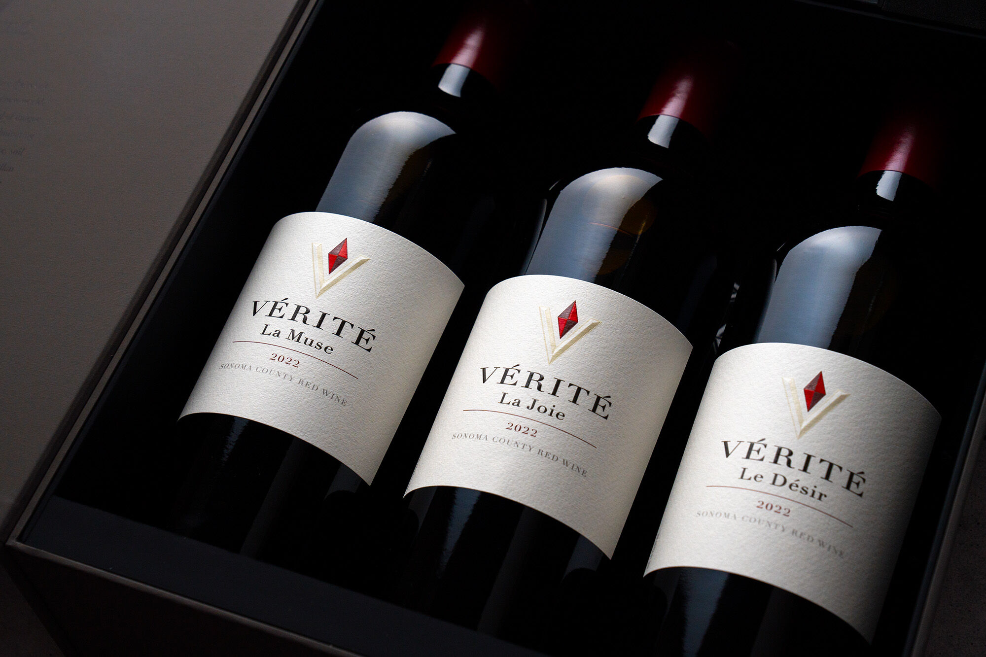 Three red wine bottles in a black gift box with white labels that read 'Vérité'