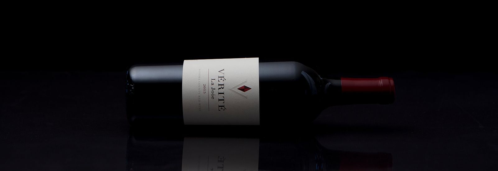 A dark wine bottle laying on its left side with a black background.