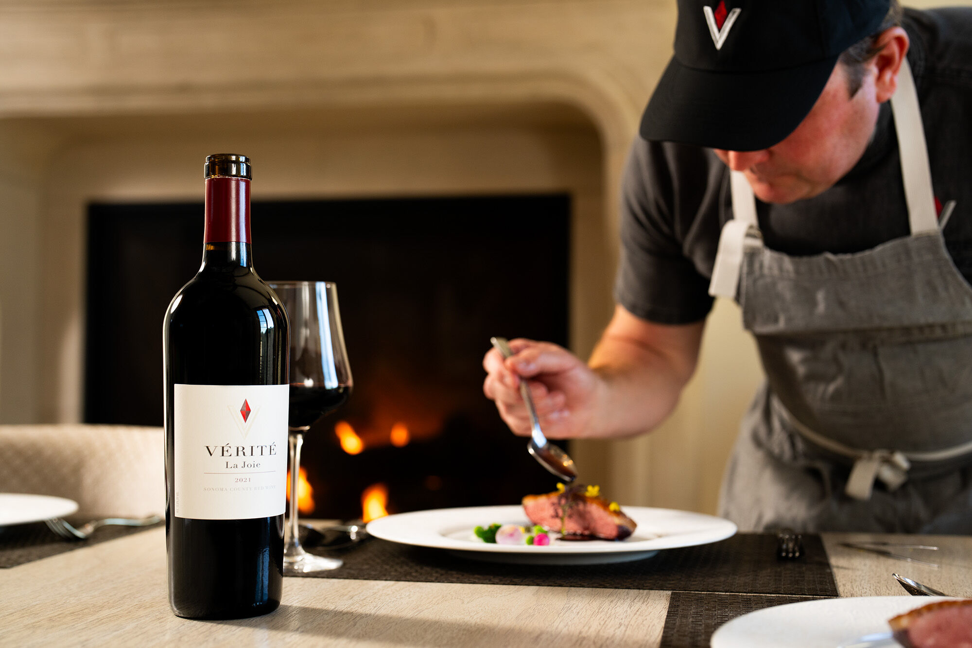La Joie wine bottle by a fireplace with a meal being plated